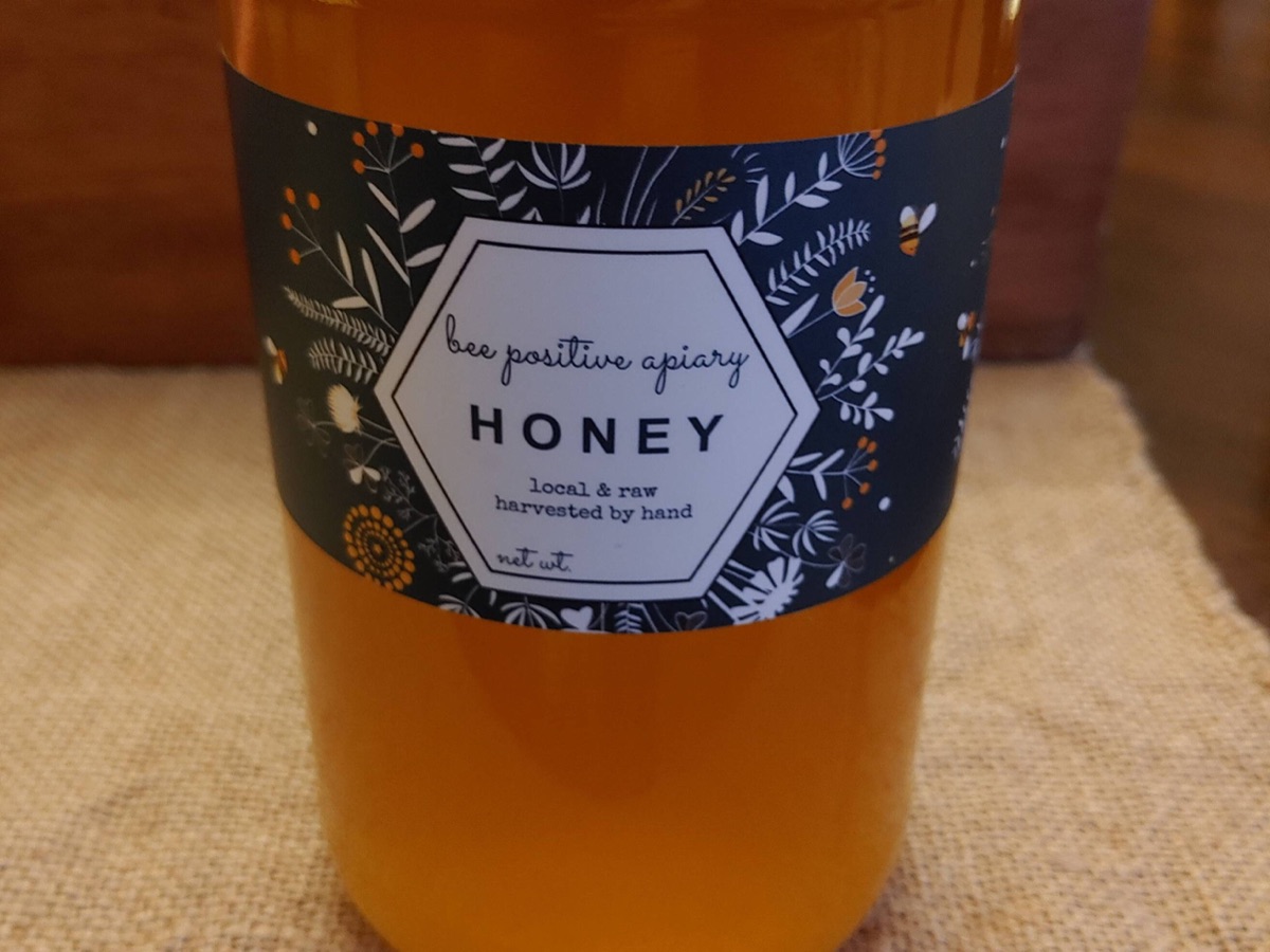 A 2 lb jar of Bee Positive Apiary honey